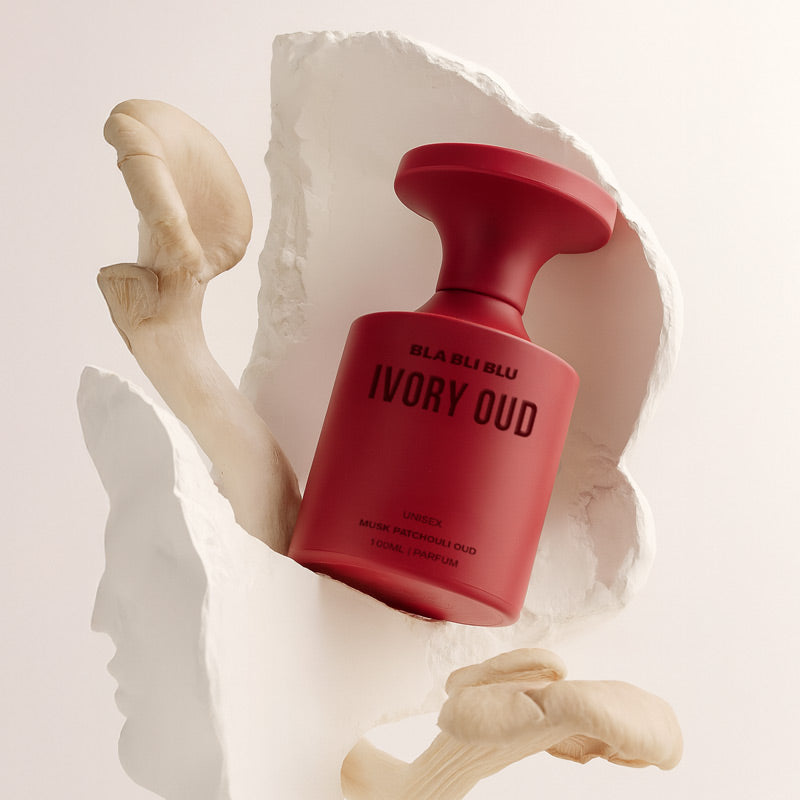 Red perfume bottle labeled 'IVORY OUD' with a neutral background