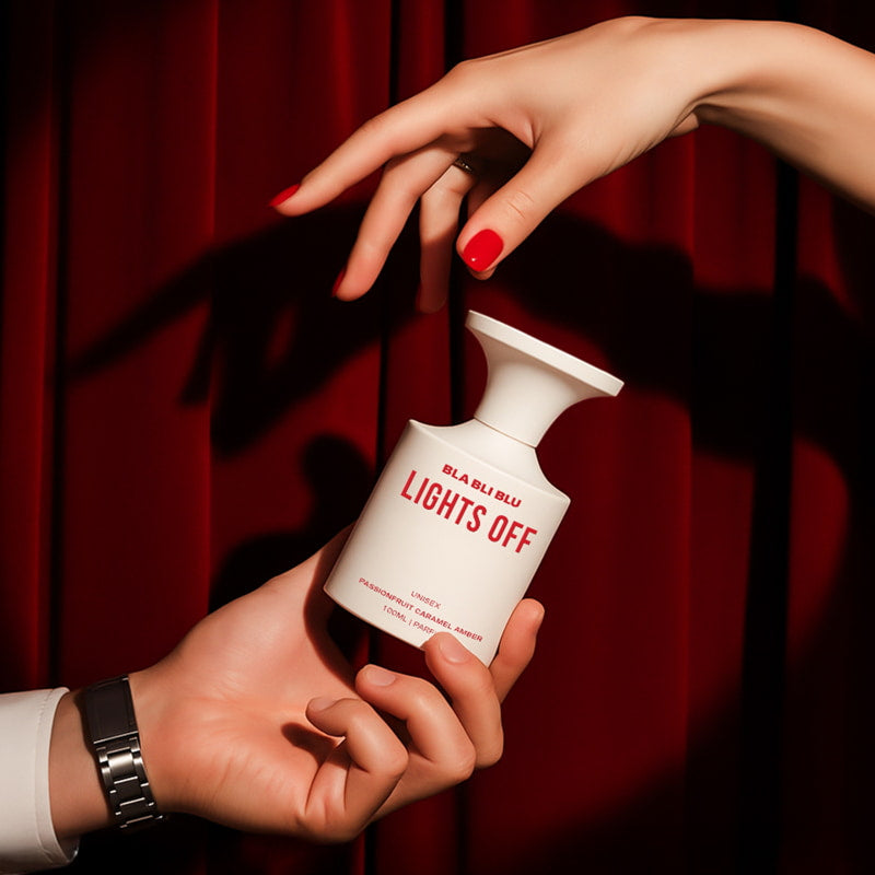 Hand holding a 'Lights Off' bottle against a red curtain background