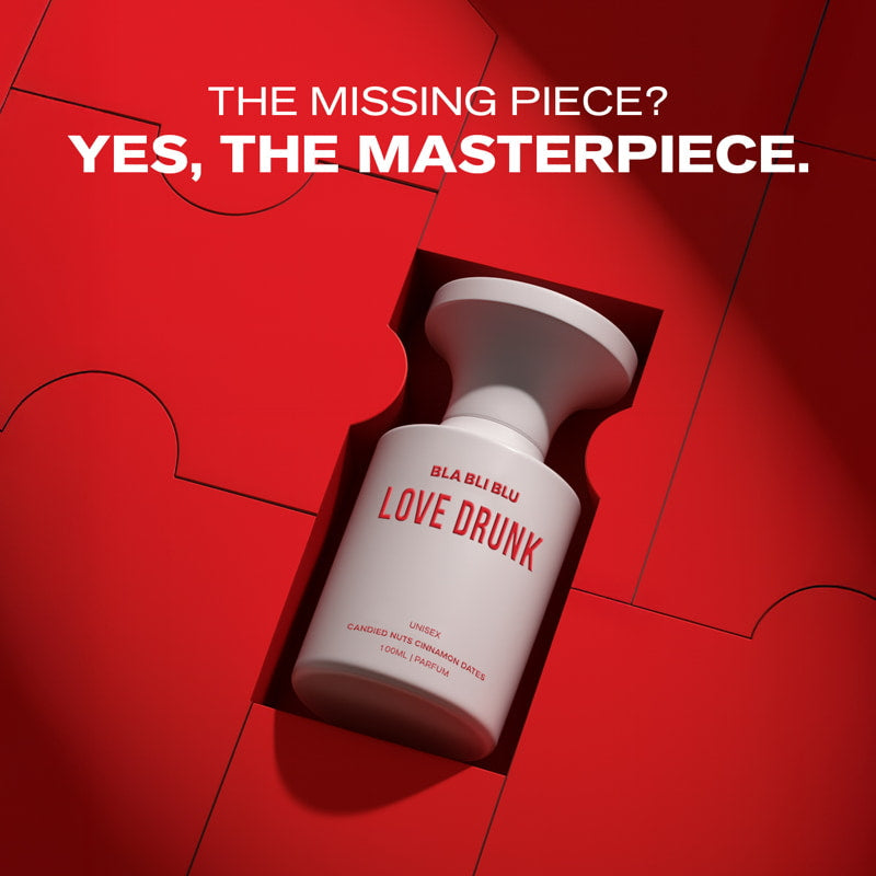 White bottle labeled 'LOVE DRUNK' on a red background with text 'THE MISSING PIECE? YES, THE MASTERPIECE.'